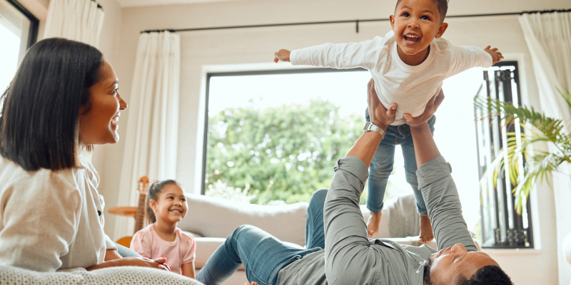 young children playing happily with mom and dad in attractive home