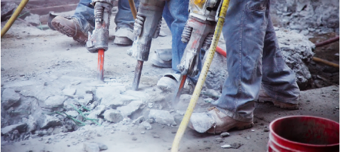 three workers using jackhammers to demolish concrete