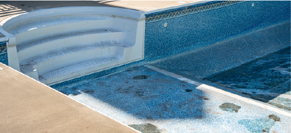 empty inground vinyl pool with wear and tear