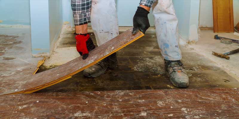 person tearing out wood flooring