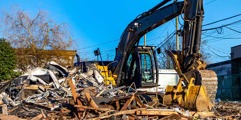 excavator tearing down commercial structure