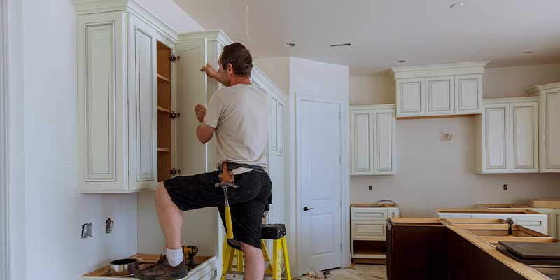 man installing new cabinets in kitchen