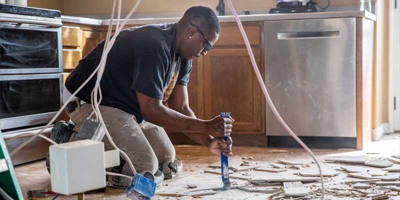 Man removing tiles from kitchen floor