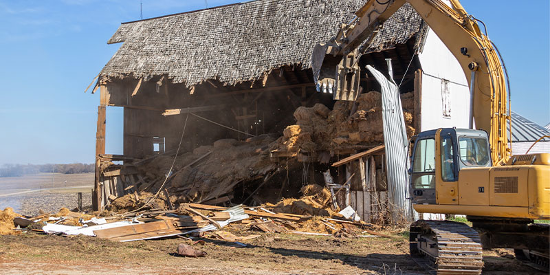 excavator demolishing barn