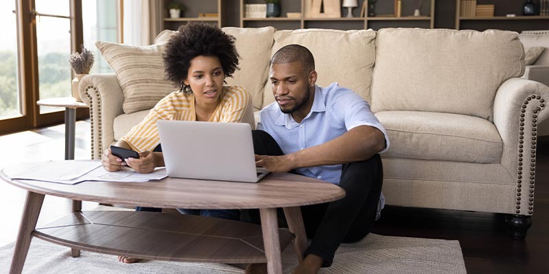 couple sitting in living room looking at computer