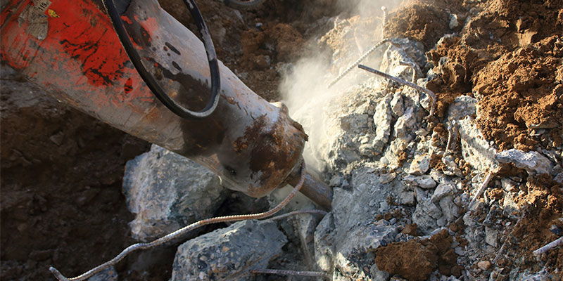 concrete slab being broken up by jackhammer attachment