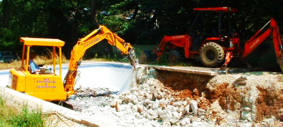 two excavators ripping out inground pool