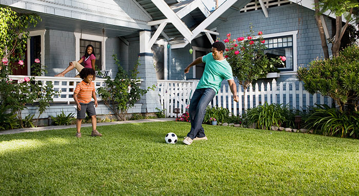 dad playing soccer with son in front yard