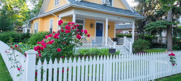 white picket fence with flower bush in front of house