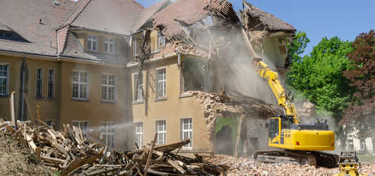 Excavator demolishing a large house
