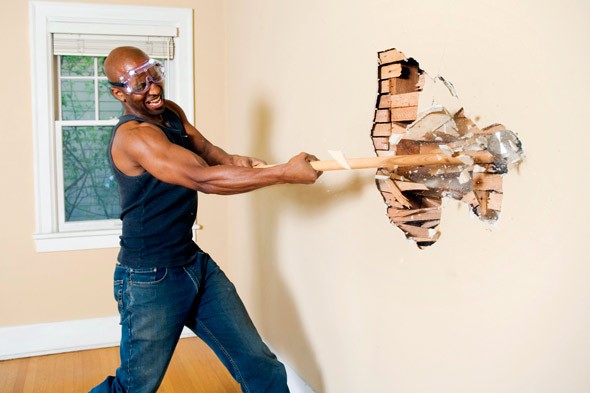 man demolishing interior wall