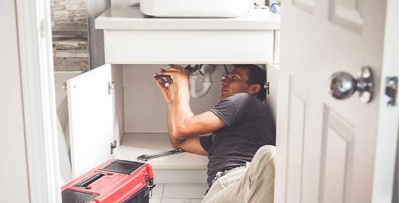 plumber working under sink