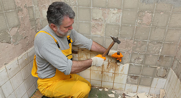 man removing bathroom shower tiles