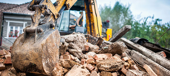 excavator scooping up structural demolition debris